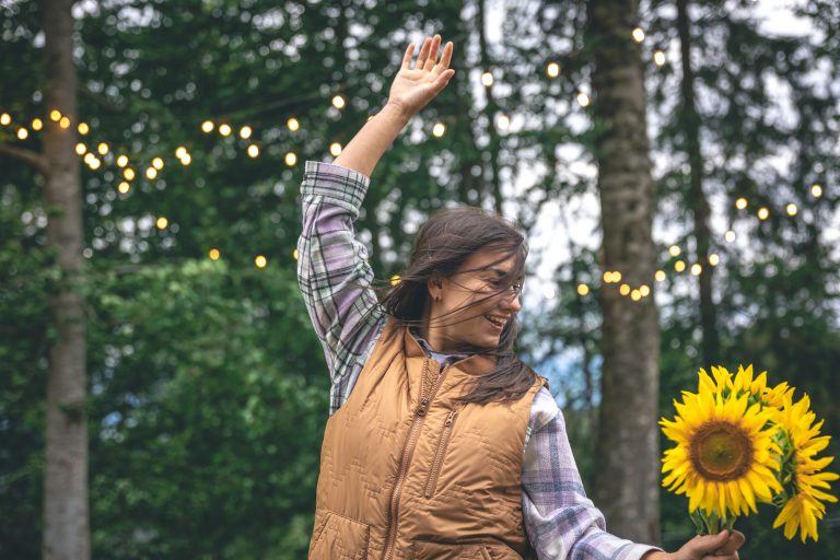A young woman with a bouquet of sunflowers on a blurred background in nature.